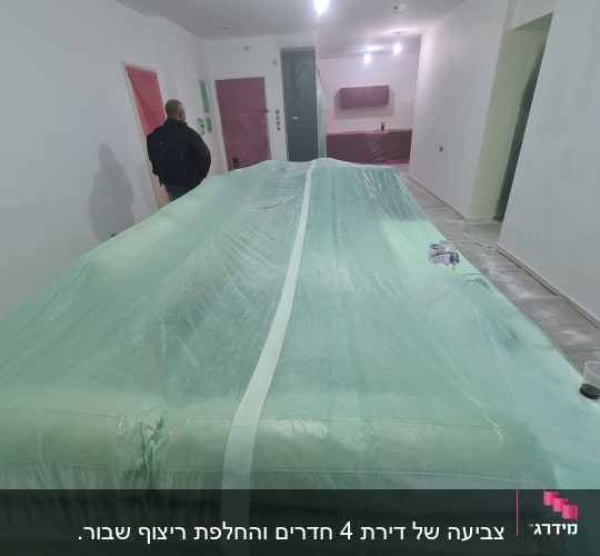חדר בשיפוץ עם כיסויים ירוקים על רהיטים